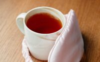 A Cup of Tea and Eye Mask on a Wooden Surface