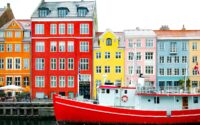 assorted-color buildings near red boat docked on port during daytime