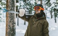 man in brown jacket and orange goggles standing on snow covered ground during daytime