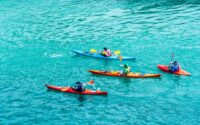 2 person riding on red kayak on body of water during daytime